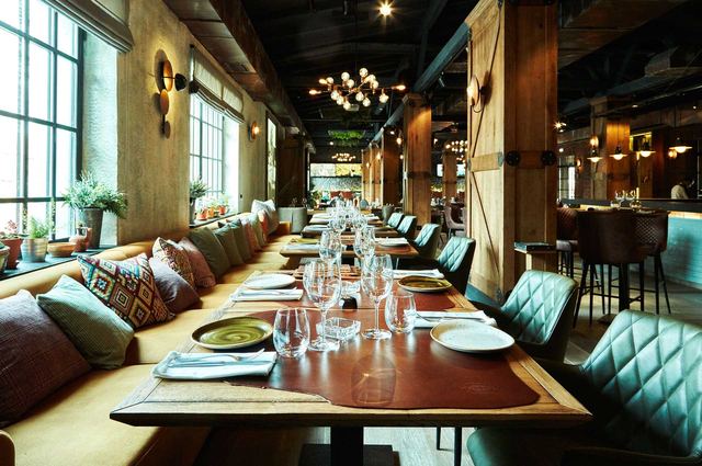 The long dining room at Bela Reka, with banquettes under tall factory windows
