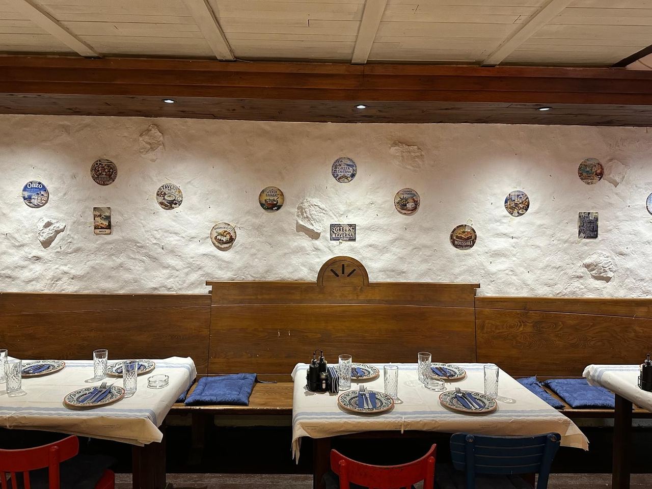Tables laid with blue-rimmed plates beneath a whitewashed wall hung with Greek plates at Me Agapi